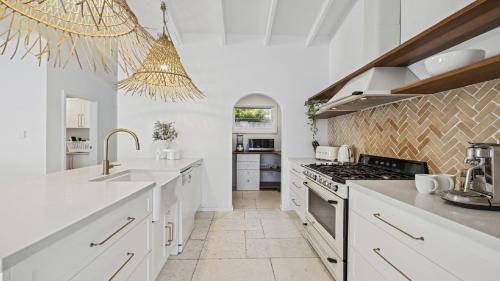 a kitchen with white counters and a stove top oven at Sojourn - Pool Oasis, Designer Home, opp Beach in Emerald Beach
