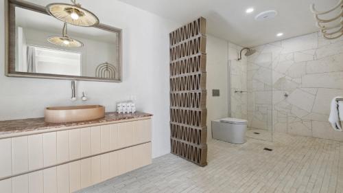 a bathroom with a sink and a mirror and a shower at Sojourn - Pool Oasis, Designer Home, opp Beach in Emerald Beach