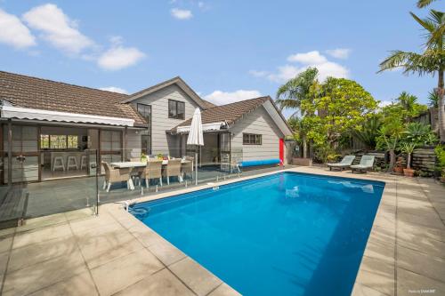 a swimming pool in front of a house at Villa with Pool in Browns Bay in Auckland