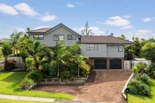 a house with palm trees in front of it at Villa with Pool in Browns Bay in Auckland