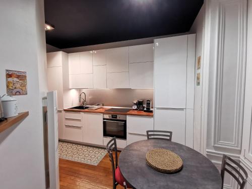 une cuisine avec des armoires blanches et une table avec des chaises dans l'établissement Le Royal Couëdic - Les Maisons de Madeleine, à Nantes