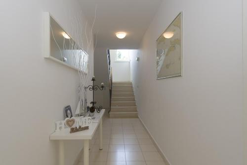 une salle de bains blanche avec deux lavabos et un escalier dans l'établissement Apartments Villa Olea, à Lumbarda