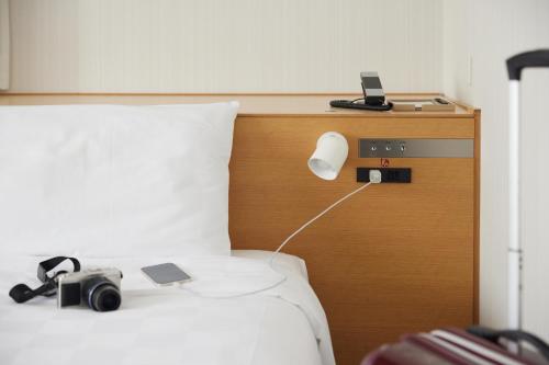 a bedroom with a bed with a camera and a lamp at Kobe Motomachi Tokyu REI Hotel in Kobe