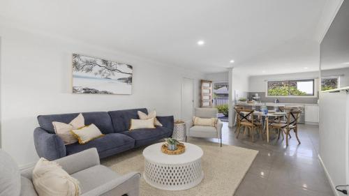 a living room with a blue couch and a table at Ripples @ Park Beach - Modern townhouse, Beach in Coffs Harbour