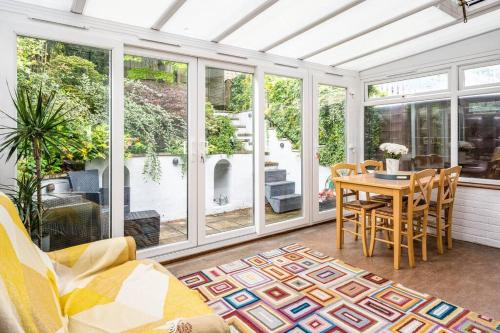 a conservatory with a table and chairs and windows at Stunning 4 Bedroom House in Central Bath in Bath