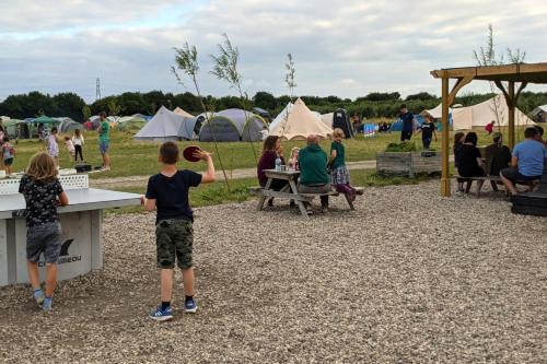a group of people sitting at tables in a park at Fallow Fields Camping, Selson Farm in Eastry