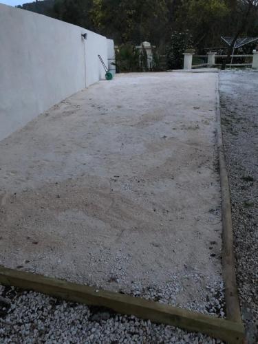 a large yard with gravel and a white wall at Mes nuits au château au domaine du pressoir in Pierrefeu-du-Var