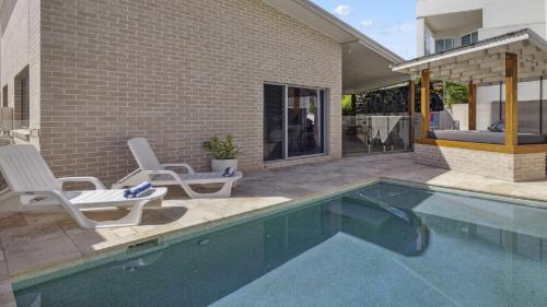 a swimming pool with two chairs next to a house at Oceanfront View - Pizza Oven, Pool, Beach in Sapphire Beach