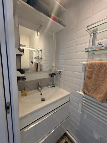 une salle de bain blanche avec un lavabo et un miroir dans l'établissement T2 moderne à 2 min de la plage, à Port-la-Nouvelle