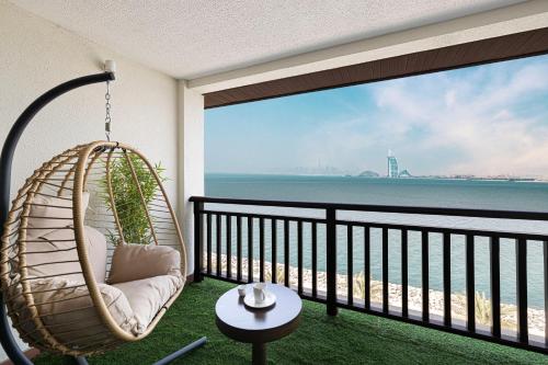 a hanging chair on a balcony with a view of the ocean at Luxury Apartments in Anantara Resort with Stunning Burj AlArab & Sea Views in Dubai