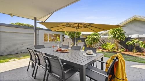 a wooden table with chairs and an umbrella at Sea Pine Cottage and Studio - Beach & village central, Family, Sleeps 8 in Sawtell