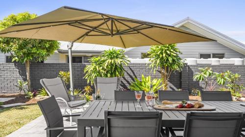 a wooden table with an umbrella on a patio at Sea Pine Cottage and Studio - Beach & village central, Family, Sleeps 8 in Sawtell