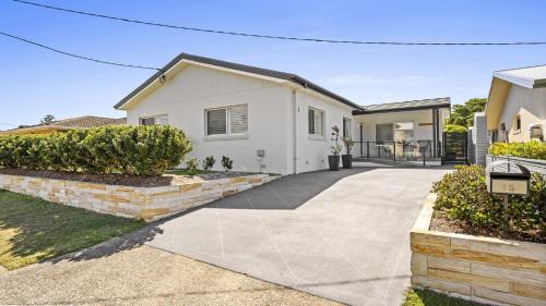 a white house with a driveway at Sea Pine Cottage and Studio - Beach & village central, Family, Sleeps 8 in Sawtell