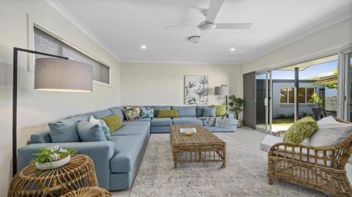 ein Wohnzimmer mit einem blauen Sofa und Stühlen in der Unterkunft Sea Pine Cottage - In the heart of Sawtell Village, Sleeps 6 in Sawtell