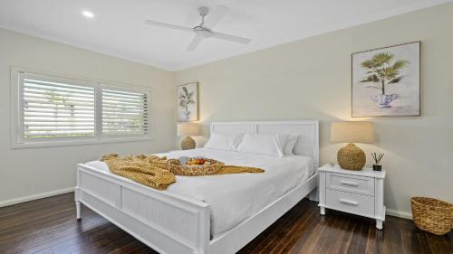ein weißes Schlafzimmer mit einem Bett, auf dem eine Obstschale steht in der Unterkunft Sea Pine Cottage - In the heart of Sawtell Village, Sleeps 6 in Sawtell