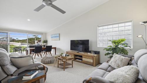 una sala de estar con un sofá y una mesa en Ballantrae 8 - Walk To Beach & Cafes Sawtell Village, en Sawtell