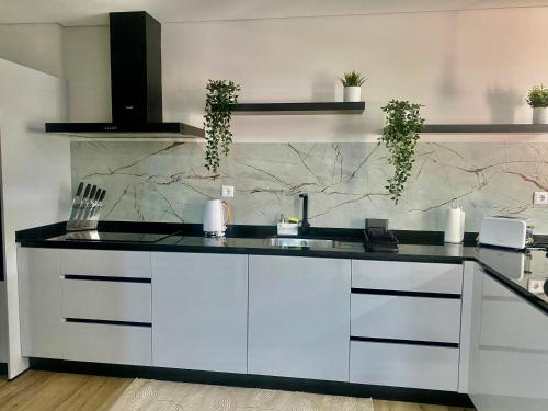 a kitchen with white cabinets and a black counter top at Casa da Boucinha in Celorico de Basto
