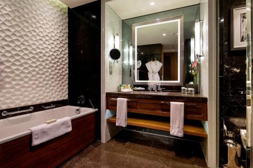 a bathroom with a tub and a sink and a mirror at Hilton Istanbul Bomonti in Istanbul