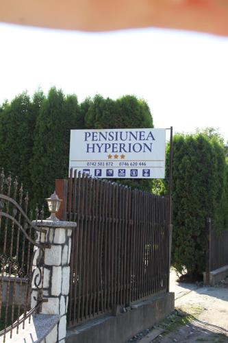 a sign in front of a fence in front of a building at Pensiunea Hyperion Cormaia in Sîngeorz-Băi