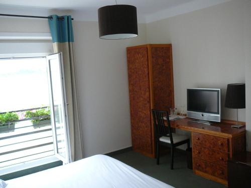 a bedroom with a desk with a television and a bed at Le Continental in Cancale