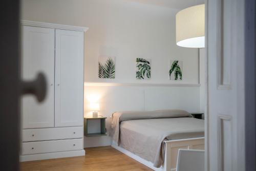 a white bedroom with a bed and plants on the wall at La Casetta di Ceci in Vibonati