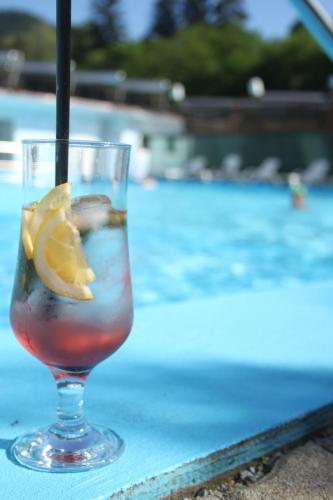 a drink sitting on a table next to a swimming pool at Pensiunea Hyperion Cormaia in Sîngeorz-Băi