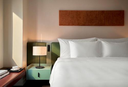 a bedroom with a bed and a table with a lamp at Signature by M Village Thợ Nhuộm in Hanoi