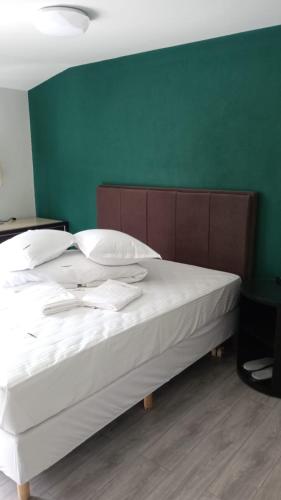 a bedroom with a white bed with a green wall at EdMont in Pietroşiţa