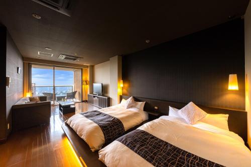 a hotel room with two beds and a balcony at Ryotei Matsubaya in Beppu