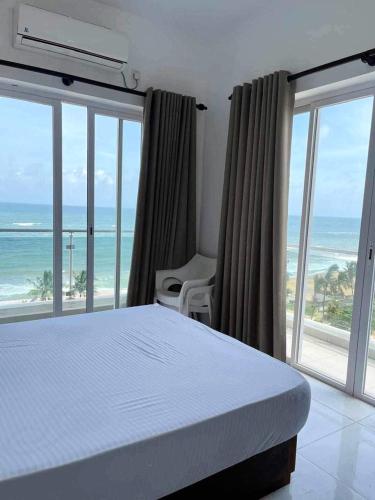 een slaapkamer met een bed en uitzicht op de oceaan bij Paradise in Mount Lavinia in Dehiwala