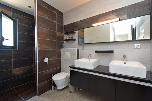 a bathroom with two sinks and a toilet and a mirror at Villa Miluva - Maison climatisée avec piscine in Lapeyrouse-Fossat
