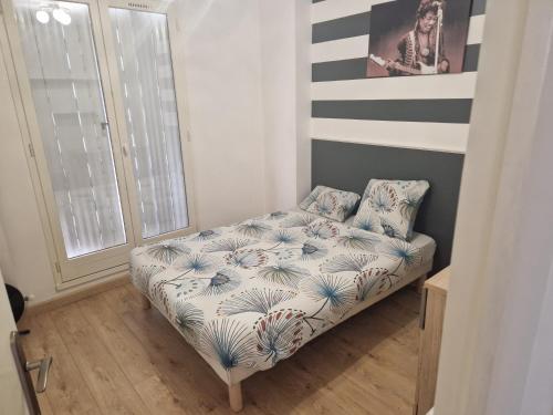 - un petit lit dans une chambre avec un mur rayé dans l'établissement Bel et lumineux Appartement - Sannois, à Sannois