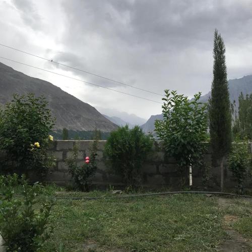 a stone retaining wall with trees and mountains in the background at Sonzal Hunza in Karimabad Hunza