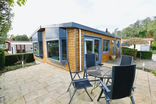 a tiny house on a patio with a table and chairs at Happy Campers in Voorthuizen