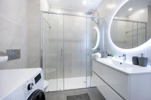 a white bathroom with a shower and a sink at O Golfinho in Lagos