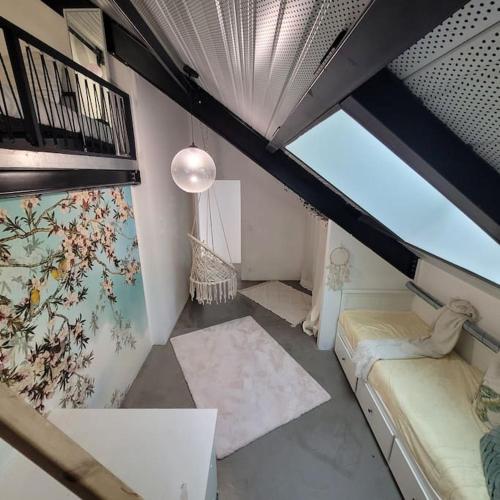 une chambre mansardée avec deux lits et une fenêtre dans l'établissement Loft élégant,spacieux,atypique, à Colombes