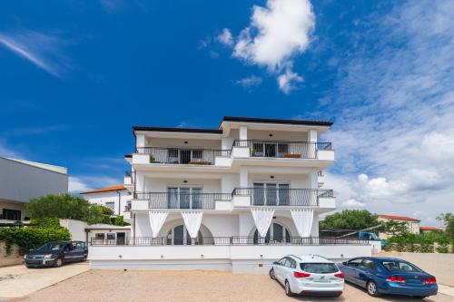 a white building with cars parked in front of it at PERLA VERDE Apartments in Krk