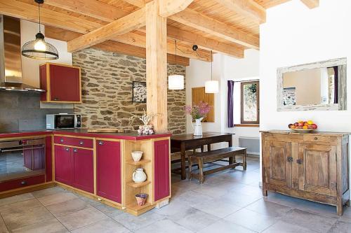 - une cuisine avec des placards rouges et une table dans l'établissement Grange rénovée aux portes du Parc des Cevennes, à Belvezet