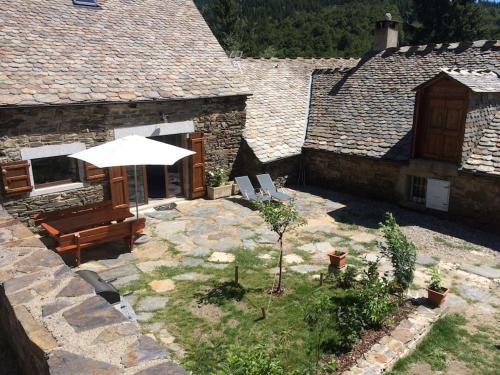 une terrasse avec un banc et un parasol dans l'établissement Grange rénovée aux portes du Parc des Cevennes, à Belvezet