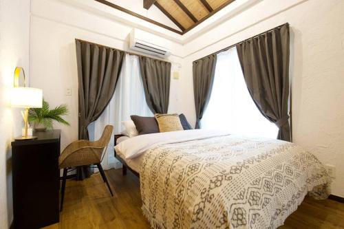 a bedroom with a bed and a desk and a window at Junglia Okinawa 崎本部戸建プール付き f in Motobu