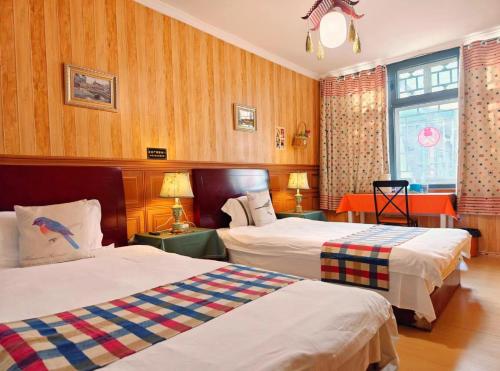 延庆县Beijing Badaling Great Wall Caos Courtyard Hostel 1VIP service 2Ancient style Chinese yard 3 only 15 minutes walk to the Badaling Great Wall 4 be your free advisor 5 offer private guided tour 6 experience local food and culutre的有两张床和一扇窗户的酒店房间