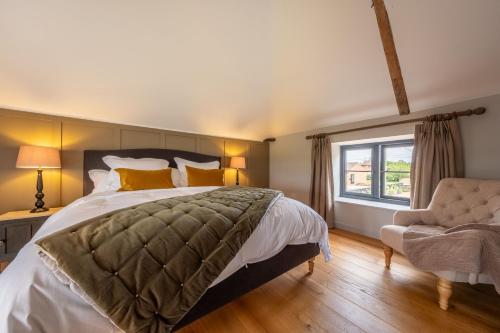 a bedroom with a bed and a chair and a window at The Coach House Happisburgh in Happisburgh