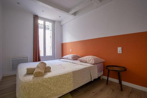 une chambre avec un lit avec un mur orange dans l'établissement Appartement T2 - Castellane/Cours Julien (climatisation et terasse), à Marseille