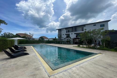 Una piscina con tumbonas al lado de un edificio. en Alisse Stay Phuket Layan, en Phuket