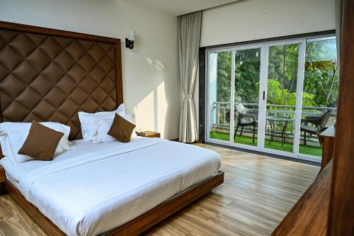 a bedroom with a large bed and a balcony at Krishna Riverside Resort in Vasad