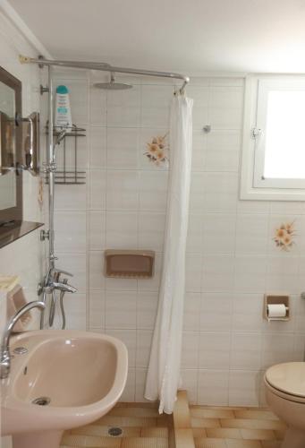 a white bathroom with a sink and a toilet at Aira Apartments in Azolimnos Syros