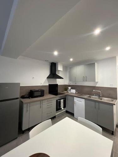 une cuisine avec des placards blancs et une table et des chaises blanches dans l'établissement La Maison Saint-Adrien, à Boulogne-sur-Mer