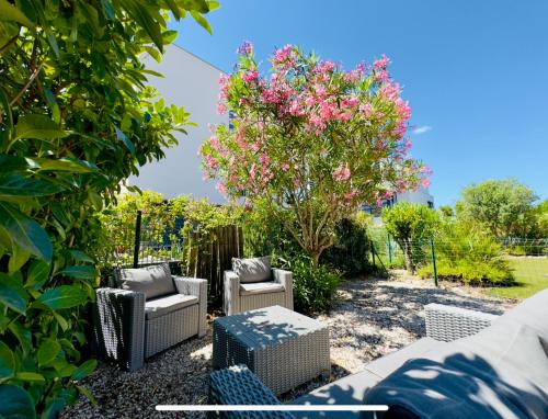un jardin avec des chaises et un arbre avec des fleurs roses dans l'établissement Havre de paix à Saint Cyprien à 300m de la plage, à Saint-Cyprien