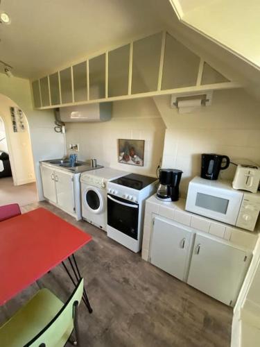 une petite cuisine avec une cuisinière et un micro-ondes dans l'établissement Appartement cosy - Dinan centre, à Dinan