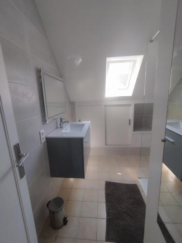 une salle de bain blanche avec un lavabo et une fenêtre dans l'établissement Maison de la fontaine, à Saint-Méloir-des-Ondes